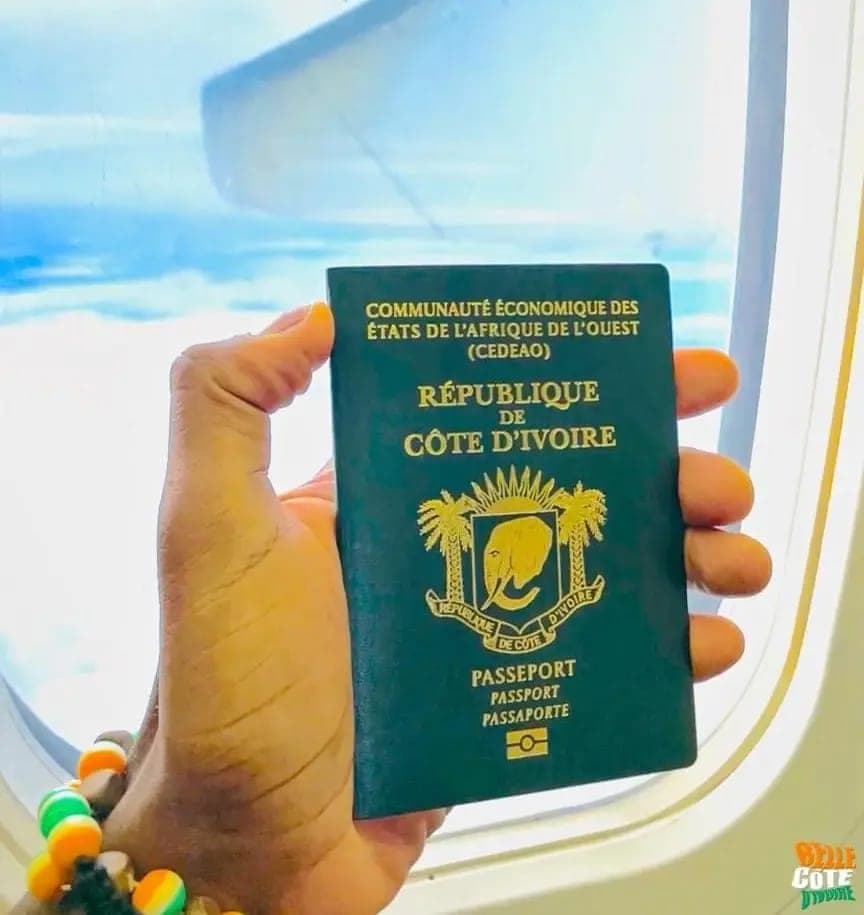 Passeport ivoirien tenu à la main devant le hublot d’un avion