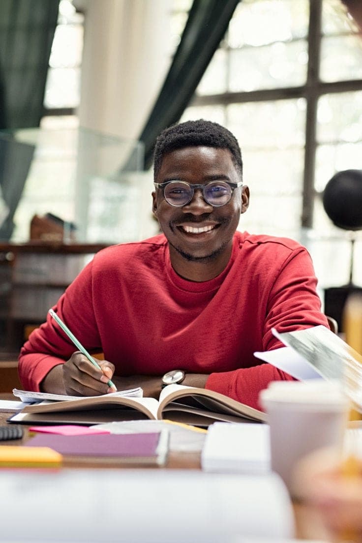Étudiant souriant préparant son dossier de candidature