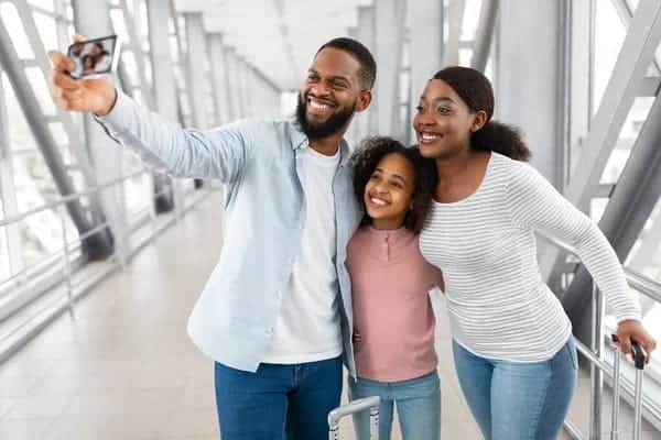 Famille souriante prenant un selfie dans un hall d’aéroport